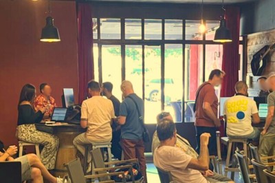 Des personnes discutent dans un espace intérieur avec des murs en briques, un écran affichant une cheminée et une ambiance…