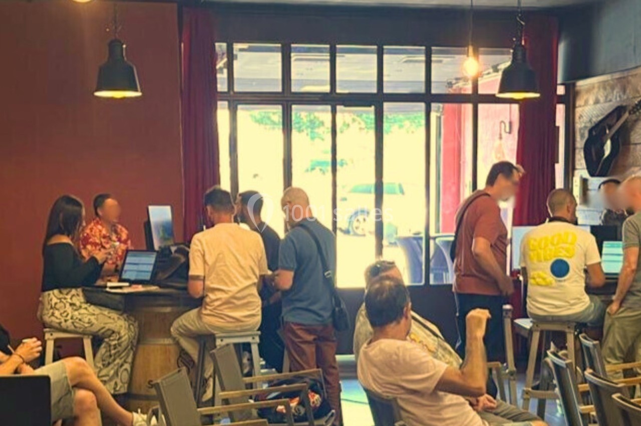 Des personnes discutent et travaillent sur des ordinateurs dans un espace intérieur lumineux avec des tables et des chaises.