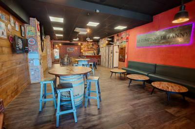 Piano en bois contre un mur décoré de cadres et d'une guitare, avec un tabouret et un micro au premier plan.