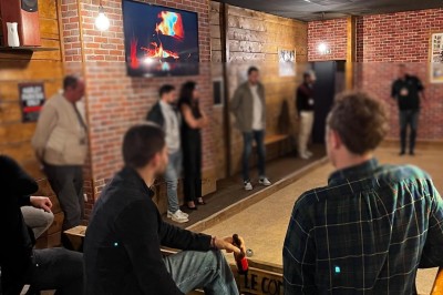 Des personnes discutent et travaillent sur des ordinateurs dans un espace intérieur lumineux avec de grandes fenêtres.