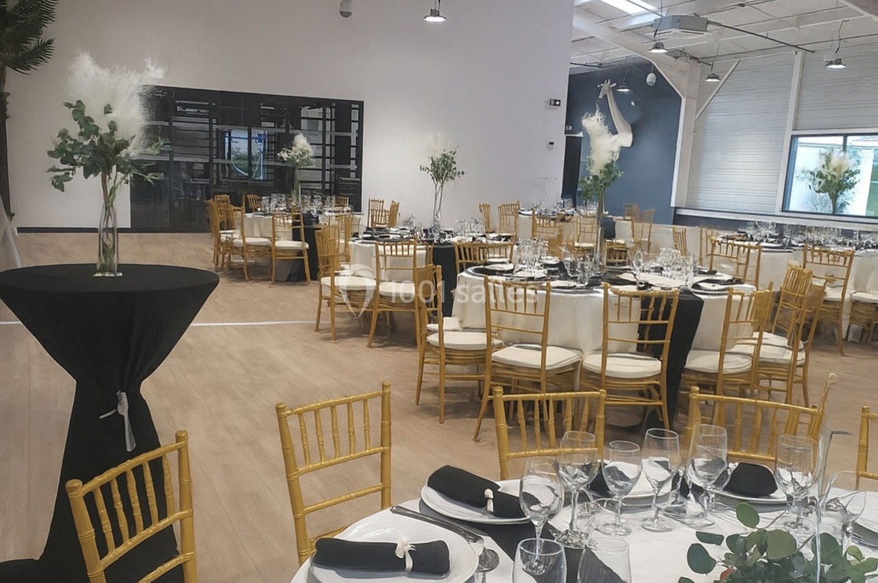 Salle de réception élégamment décorée avec des tables rondes, des chaises dorées et des centres de table floraux.