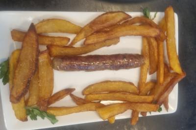 Bol de soupe garnie de coriandre sur une table en marbre avec des couverts, des verres et une salière en arrière-plan.