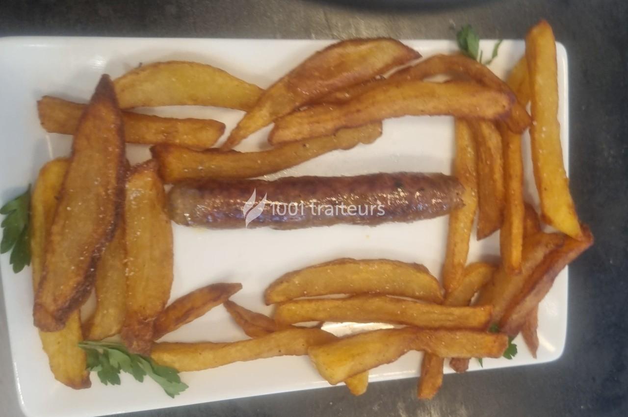 Assiette contenant une saucisse grillée entourée de frites dorées, présentée sur un plat rectangulaire blanc.