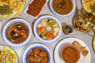 Bol de soupe garnie de coriandre sur une table en marbre avec des couverts, des verres et une salière en arrière-plan.
