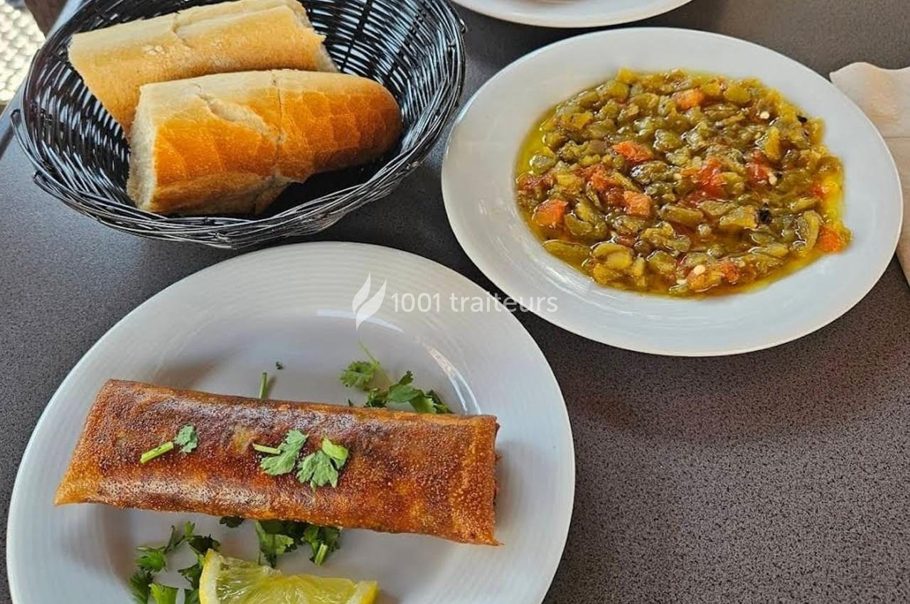 Assiette avec un rouleau croustillant garni de coriandre, accompagnée de pain et d'un plat de légumes mijotés.