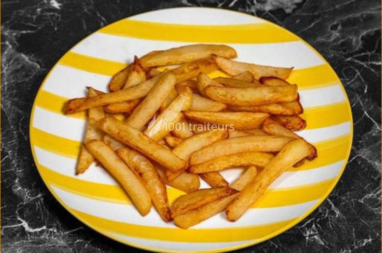 Assiette rayée jaune et blanche contenant des frites dorées sur une table en marbre noir.