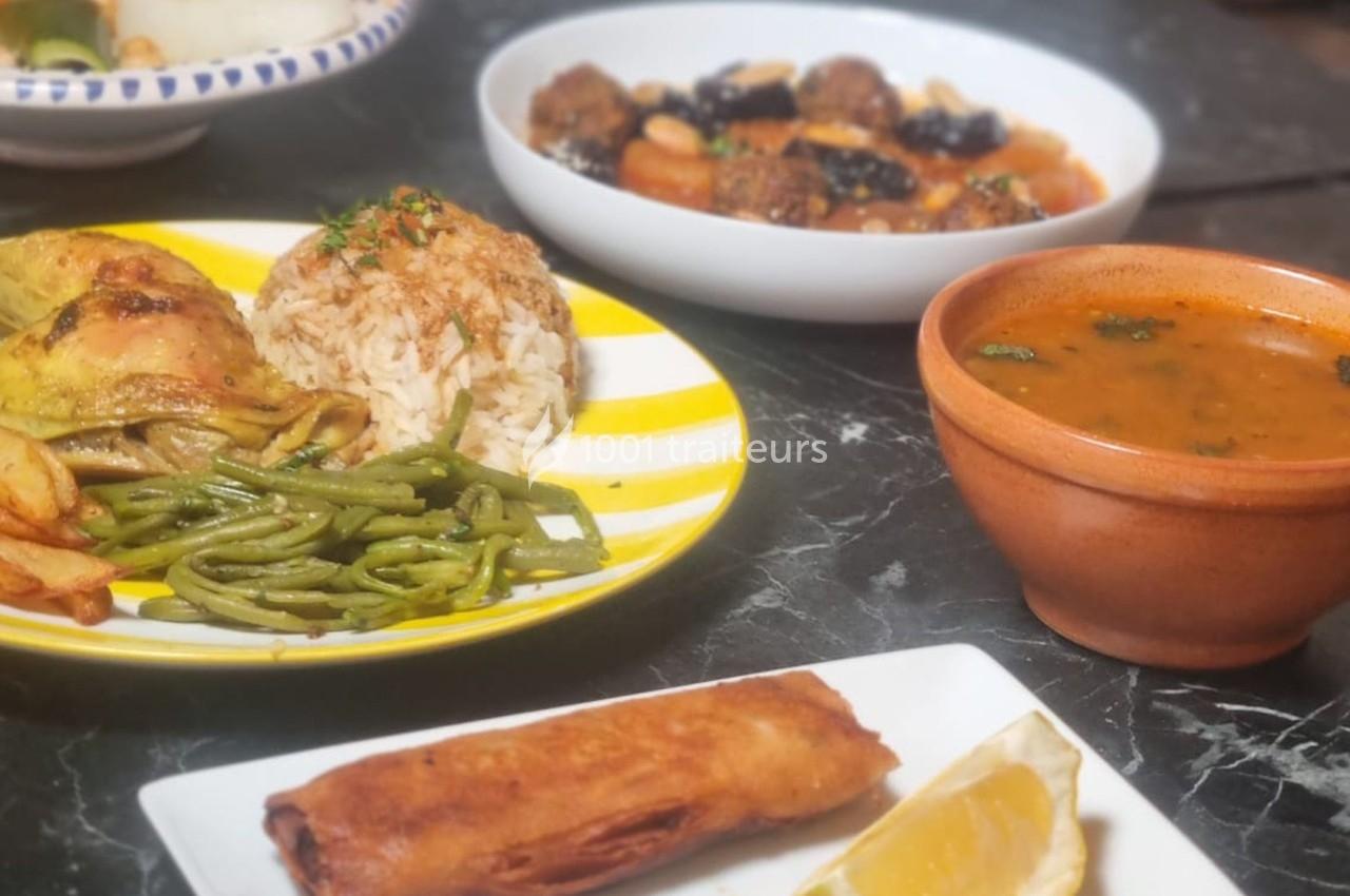 Assiette de poulet avec riz, haricots verts, soupe, rouleau frit et citron, accompagnés de plats en arrière-plan.