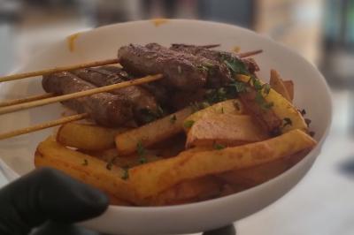 Bol de soupe garnie de coriandre sur une table en marbre avec des couverts, des verres et une salière en arrière-plan.