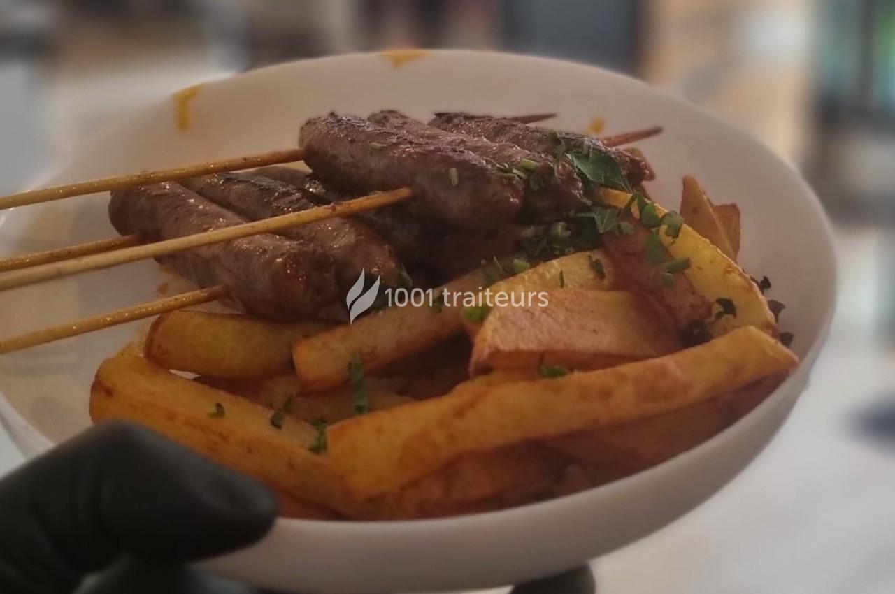 Assiette contenant des brochettes de viande grillée et des frites, garnie de persil haché.