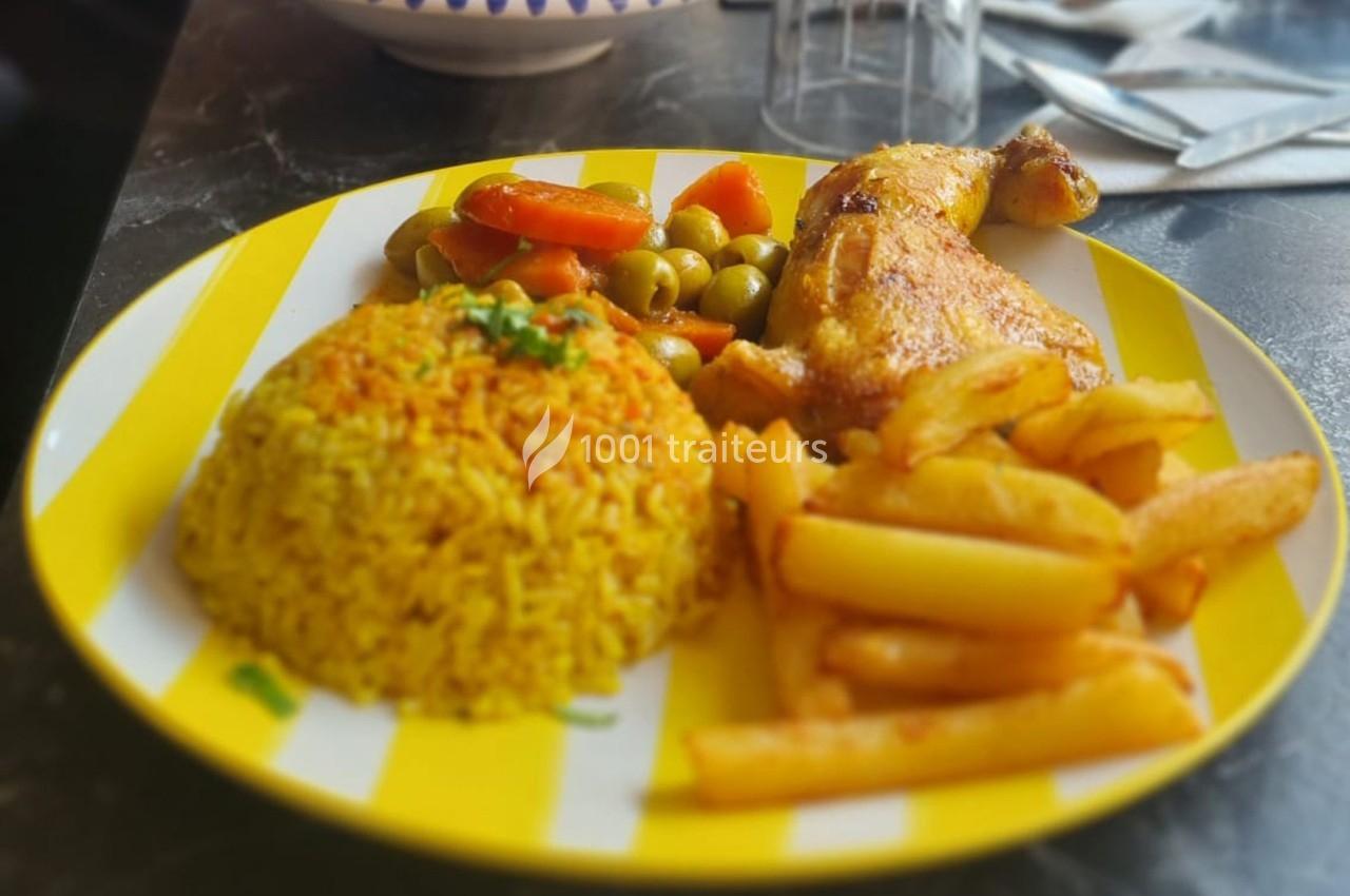 Assiette contenant du riz jaune, des frites, un morceau de poulet rôti, des légumes et des olives vertes.