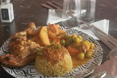 Bol de soupe garnie de coriandre sur une table en marbre avec des couverts, des verres et une salière en arrière-plan.