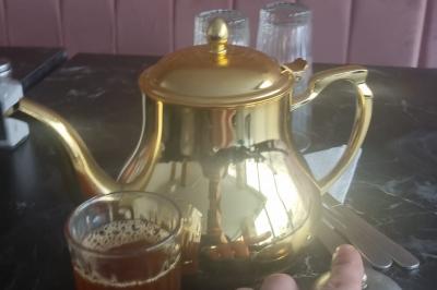 Bol de soupe garnie de coriandre sur une table en marbre avec des couverts, des verres et une salière en arrière-plan.