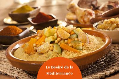 Bol de soupe garnie de coriandre sur une table en marbre avec des couverts, des verres et une salière en arrière-plan.