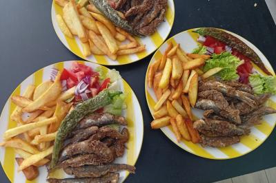 Bol de soupe garnie de coriandre sur une table en marbre avec des couverts, des verres et une salière en arrière-plan.