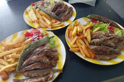 Bol de soupe garnie de coriandre sur une table en marbre avec des couverts, des verres et une salière en arrière-plan.