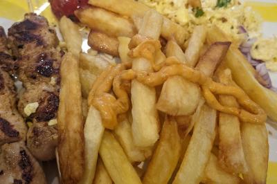 Bol de soupe garnie de coriandre sur une table en marbre avec des couverts, des verres et une salière en arrière-plan.