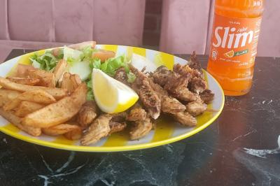 Bol de soupe garnie de coriandre sur une table en marbre avec des couverts, des verres et une salière en arrière-plan.