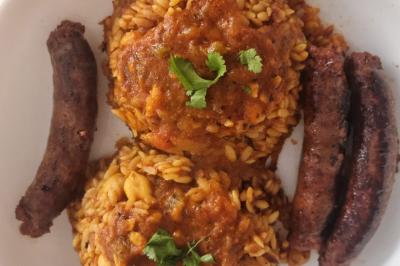 Bol de soupe garnie de coriandre sur une table en marbre avec des couverts, des verres et une salière en arrière-plan.