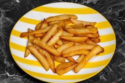 Bol de soupe garnie de coriandre sur une table en marbre avec des couverts, des verres et une salière en arrière-plan.