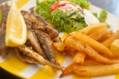 Bol de soupe garnie de coriandre sur une table en marbre avec des couverts, des verres et une salière en arrière-plan.