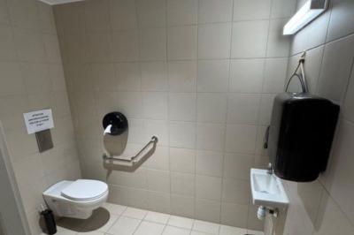 Salle décorée avec des guirlandes colorées et des lanternes, tables dressées pour un événement festif près de grandes baies…