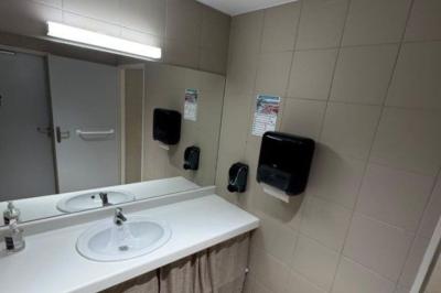 Salle décorée avec des guirlandes colorées et des lanternes, tables dressées pour un événement festif près de grandes baies…