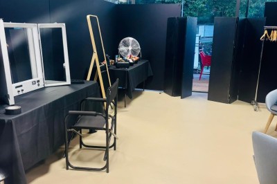 Salle décorée avec des guirlandes colorées et des lanternes, tables dressées pour un événement festif près de grandes baies…