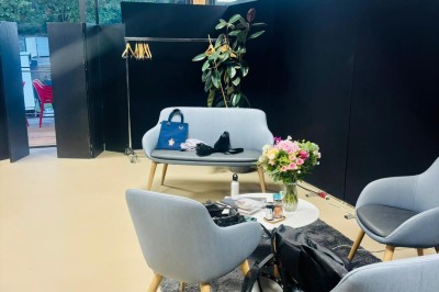 Salle décorée avec des guirlandes colorées et des lanternes, tables dressées pour un événement festif près de grandes baies…