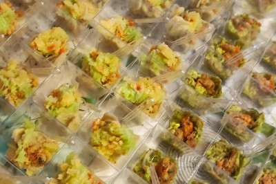 Assiette composée de rillettes de poisson servies dans des coques de noix de coco, accompagnées d'avocat et de crudités.