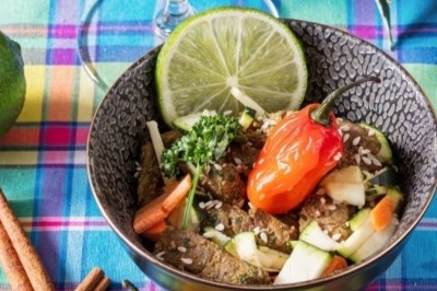 Assiette composée de rillettes de poisson servies dans des coques de noix de coco, accompagnées d'avocat et de crudités.