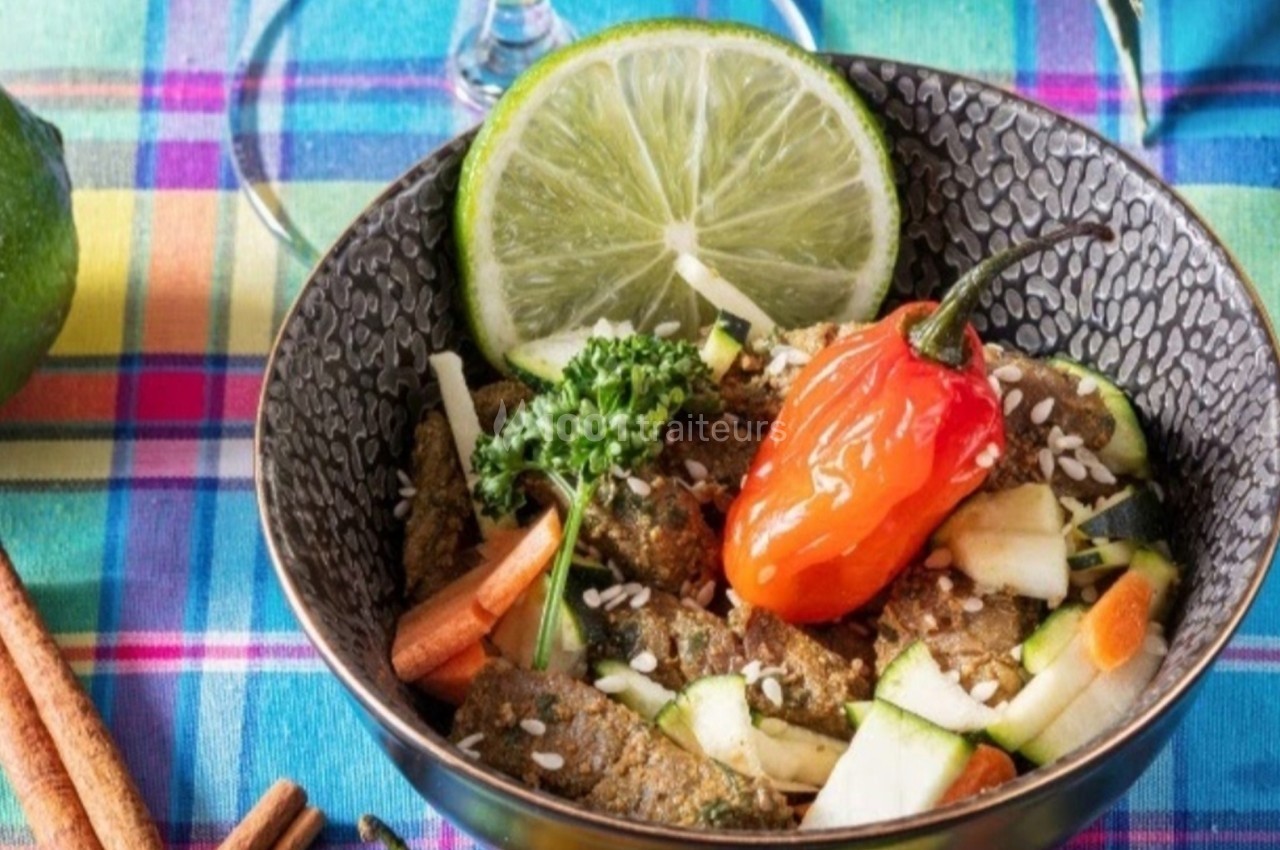 Bol de légumes frais avec herbes, graines, rondelle de citron vert et piment rouge, posé sur une nappe colorée.