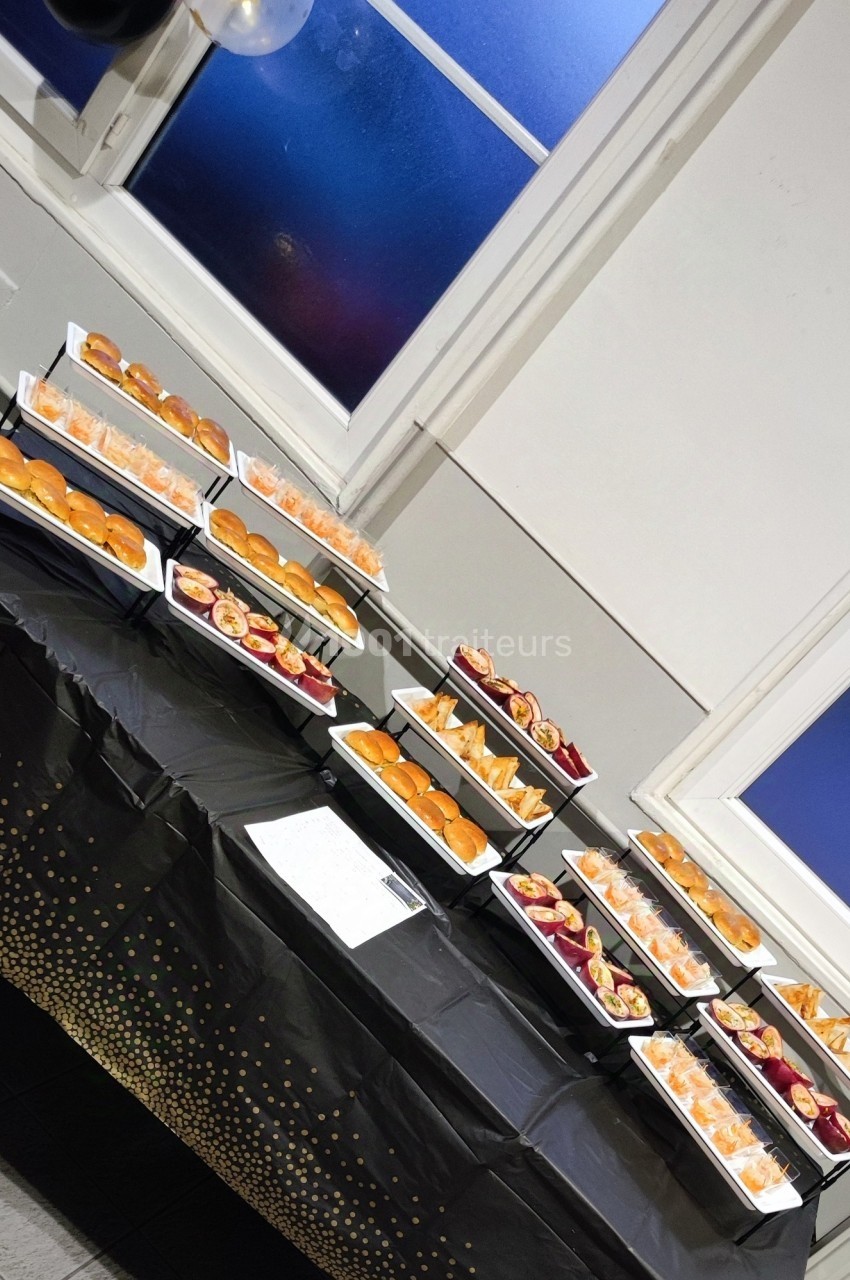 Plateau de buffet avec divers assortiments de mini-sandwichs et amuse-bouches disposés sur une nappe noire.