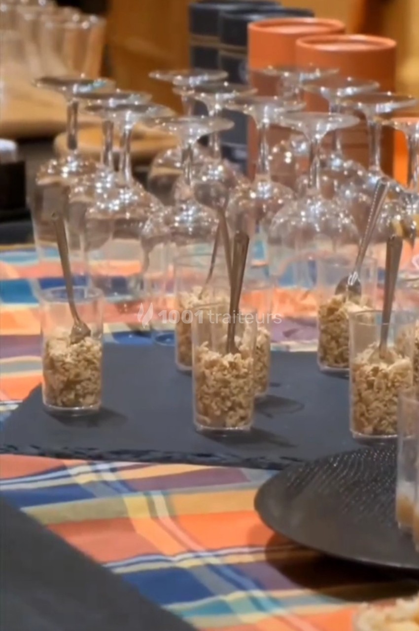 Verres à pied et verrines contenant des céréales avec cuillères, disposés sur une table recouverte d'une nappe colorée.