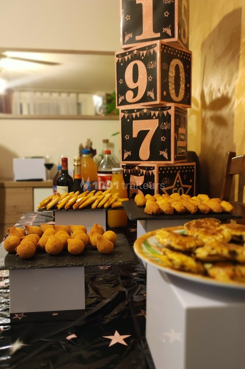 Table décorée avec des amuse-bouches, boissons et cubes numérotés empilés en arrière-plan.