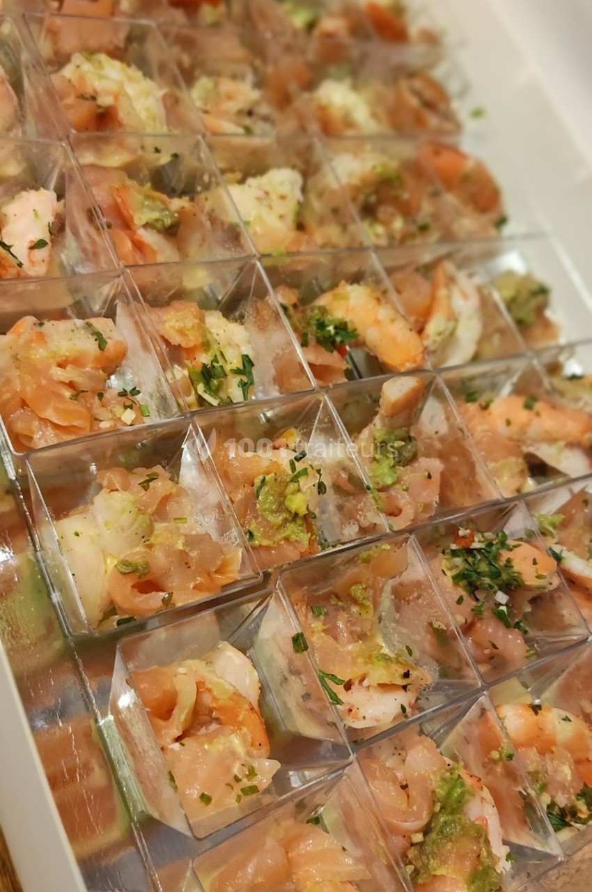 Assortiment de verrines contenant des crevettes, saumon et herbes fraîches, disposées en rangées dans un plateau.