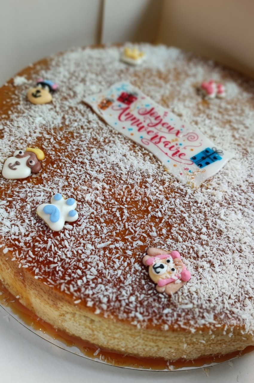 Gâteau décoré de sucre râpé, figurines colorées et une plaque ’Joyeux Anniversaire’ en sucre.