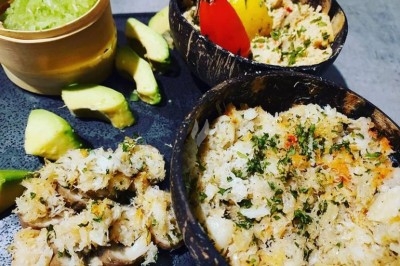 Miniature Traiteur Courbevoie (Hauts-de-Seine) - Doucines Créoles #20 Assiettes de crabe émietté assaisonné, servies dans des coques de noix de coco avec des tranches d'avocat et une sauce verte.