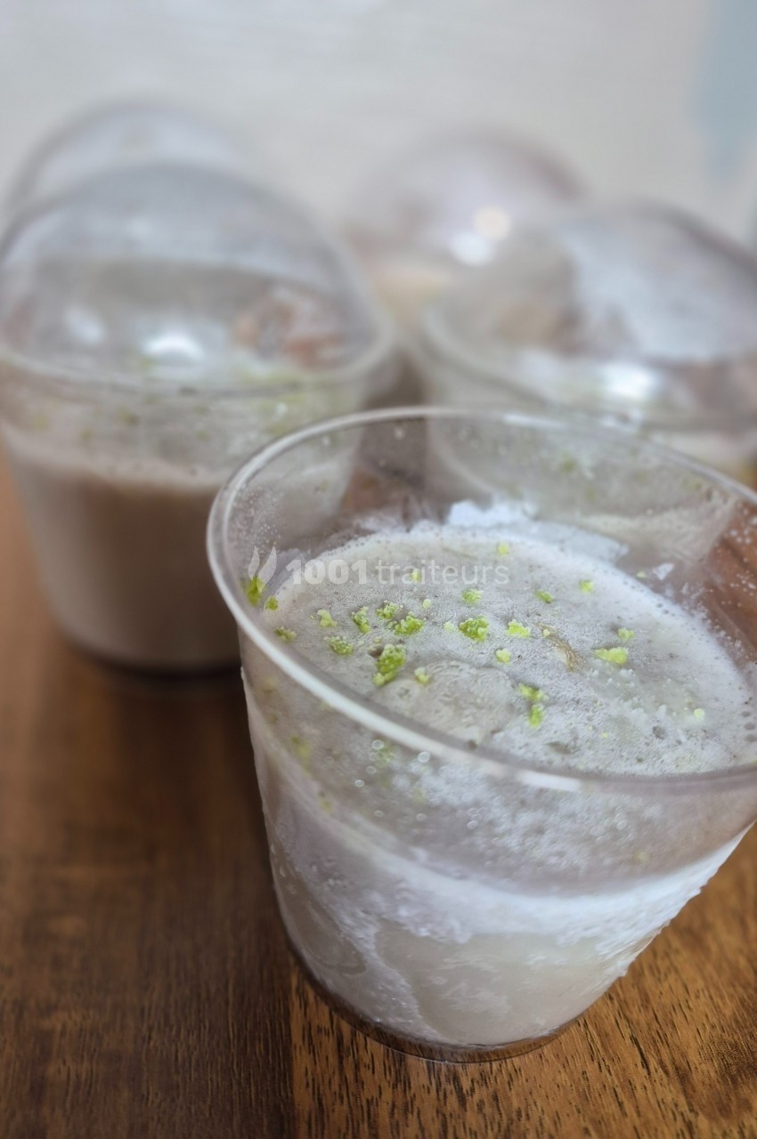 Desserts glacés en gobelets transparents, garnis de zestes verts, posés sur une table en bois.