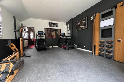 Piscine intérieure avec toit en verre, entourée de baies vitrées donnant sur un jardin avec parasols bleus.