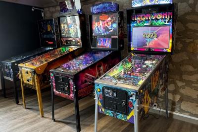 Piscine intérieure avec toit en verre, entourée de baies vitrées donnant sur un jardin avec parasols bleus.