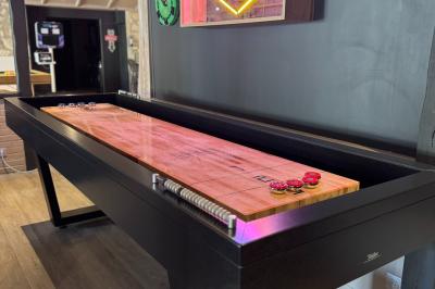 Piscine intérieure avec toit en verre, entourée de baies vitrées donnant sur un jardin avec parasols bleus.