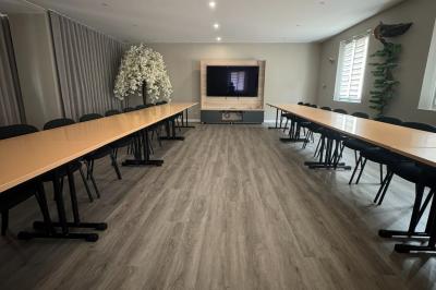 Piscine intérieure avec toit en verre, entourée de baies vitrées donnant sur un jardin avec parasols bleus.