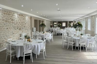 Balancelle en bois rustique sur une pelouse artificielle, avec des bâtiments en pierre et un ciel dégagé en arrière-plan.