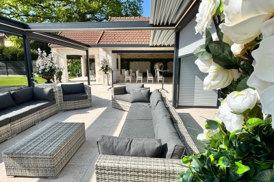 Grande table décorée pour un repas festif, avec nappes en toile de jute, serviettes pliées et centres de table fleuris.