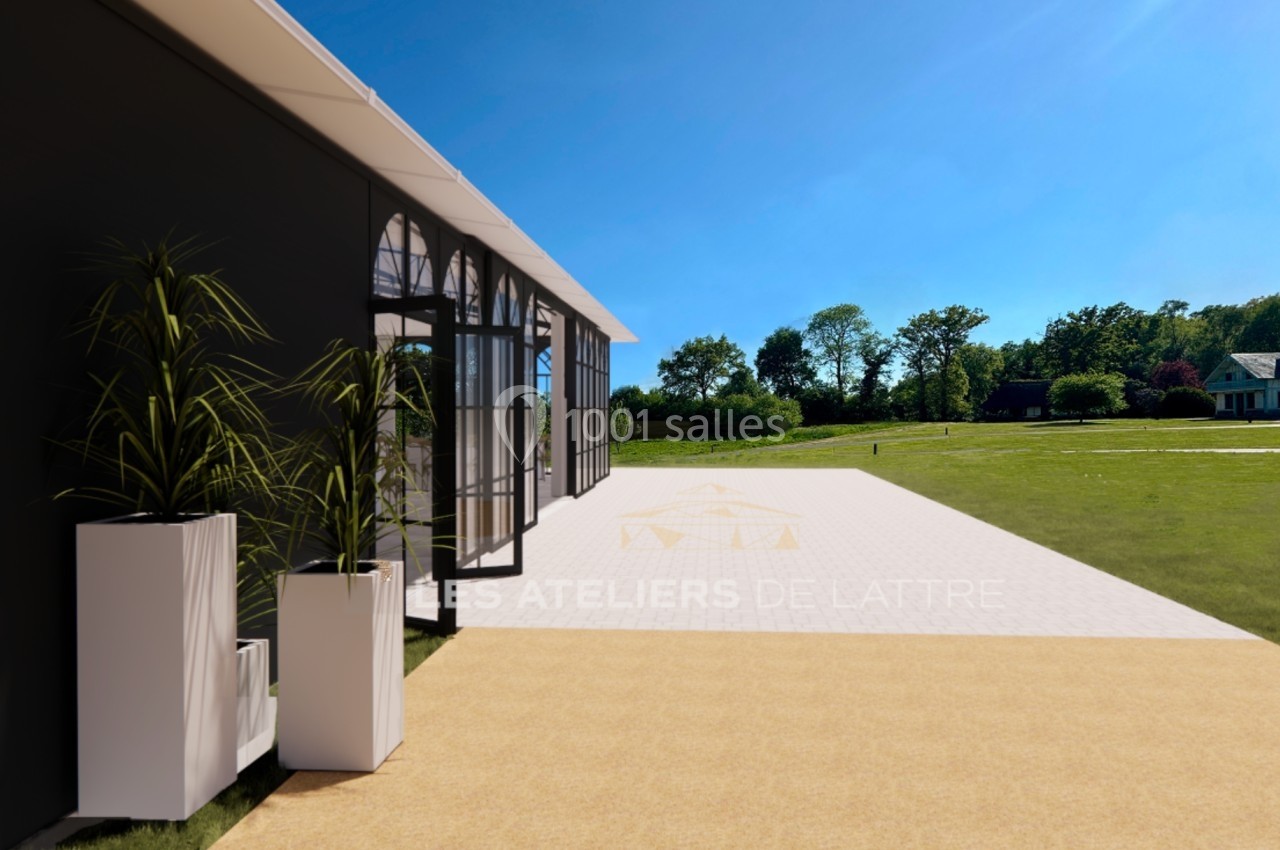 Extérieur d'un bâtiment moderne avec de grandes baies vitrées, entouré de plantes et donnant sur un espace vert.