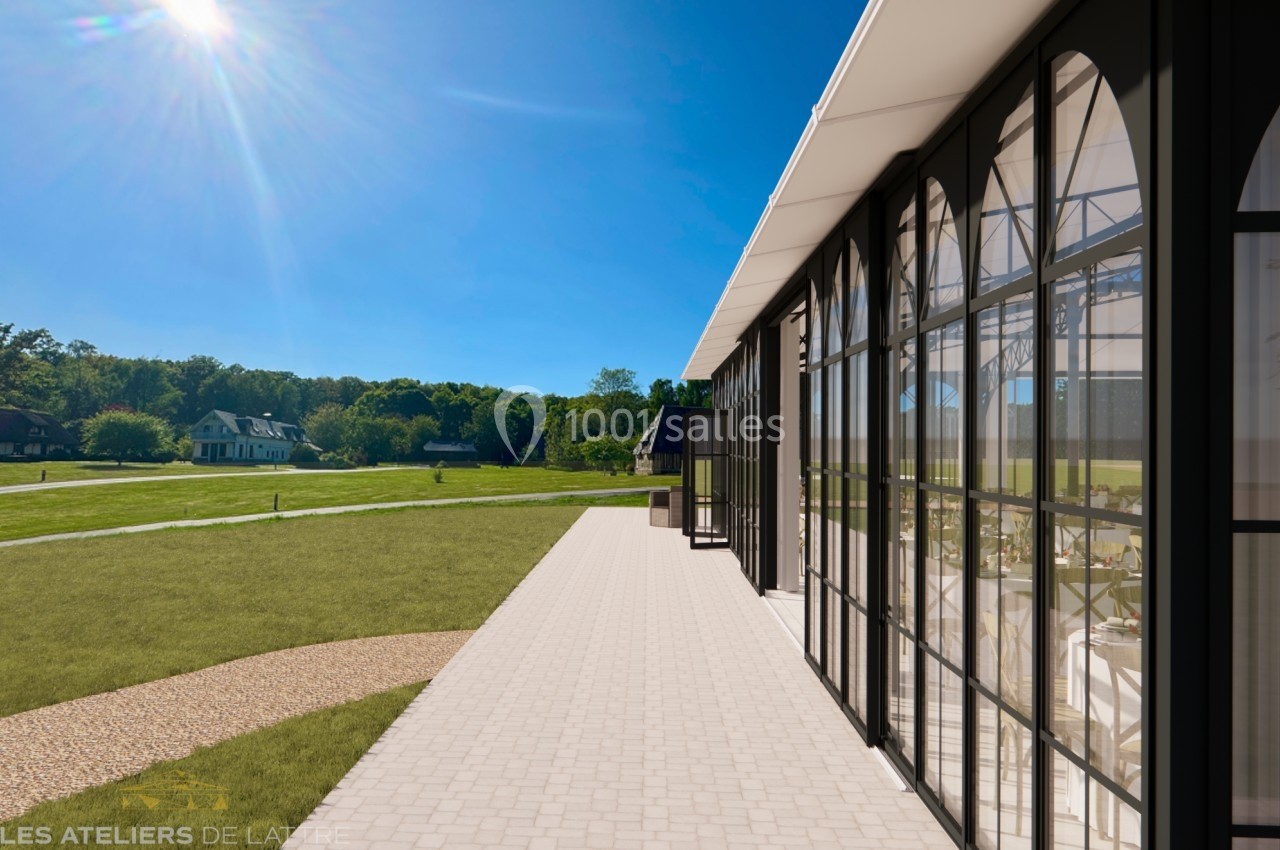 Façade vitrée d'un bâtiment moderne donnant sur un espace vert par une journée ensoleillée.
