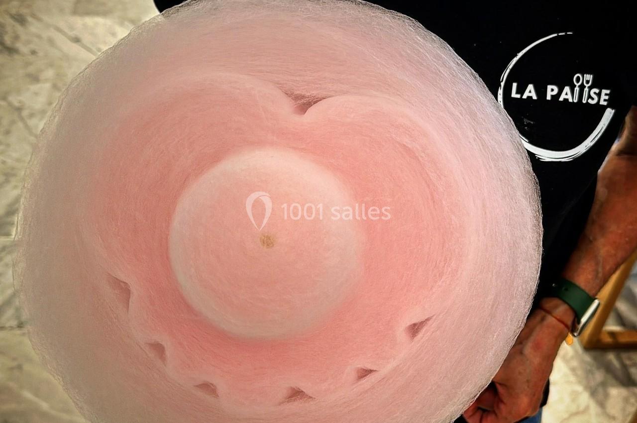 Barbe à papa rose en forme de fleur tenue par une personne portant un t-shirt noir.