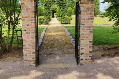 Panier en osier posé au sol devant un grand miroir, avec un lit et une lampe en arrière-plan dans une chambre.