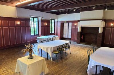 Salle avec des tables rondes et rectangulaires recouvertes de nappes blanches, entourées de chaises noires.