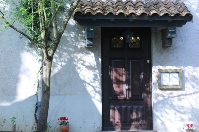 Grande maison blanche à deux étages avec volets bleus, entourée d'arbres et d'un jardin verdoyant.